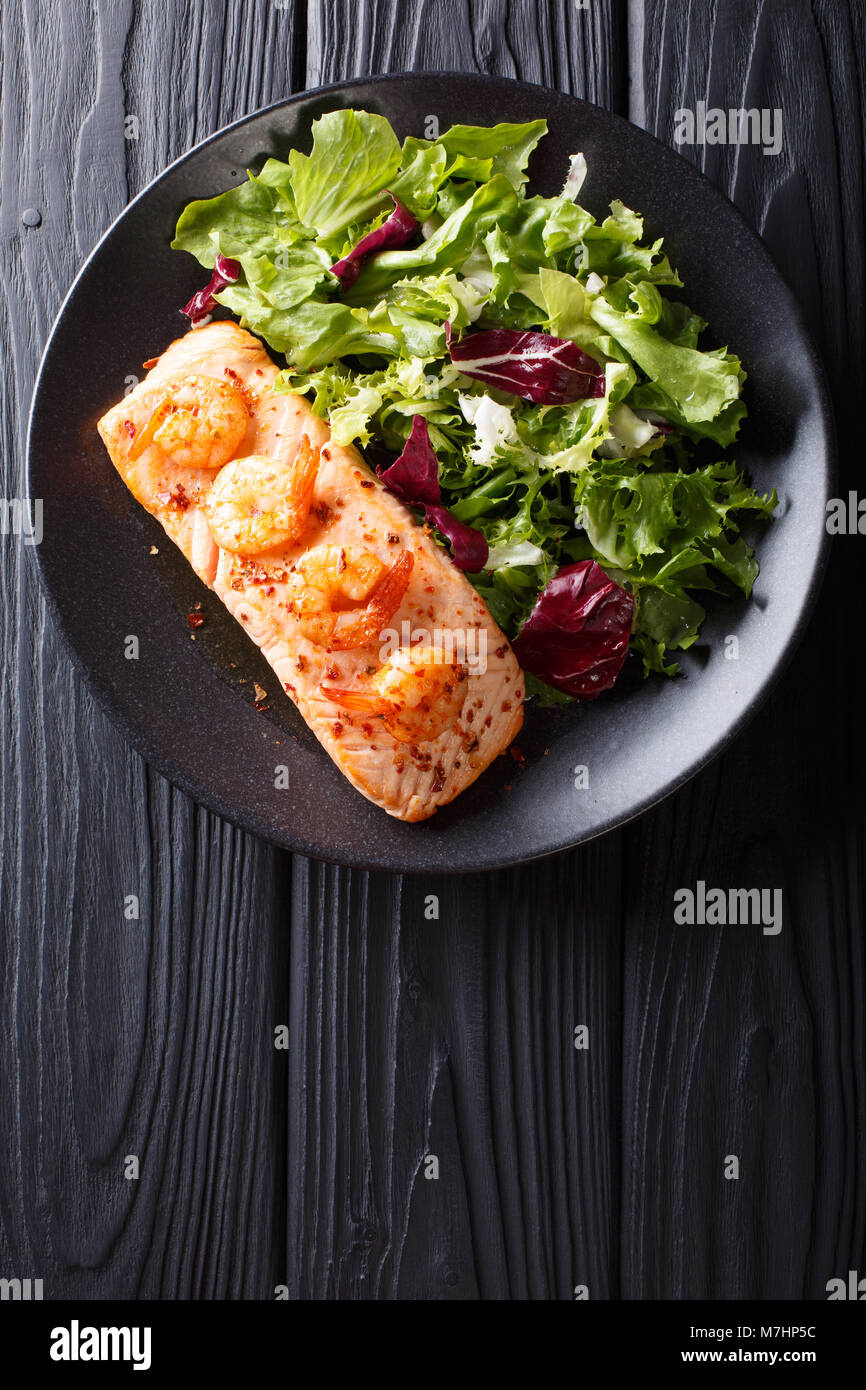 Saumon au four aux gambas et sa sauce au miel avec un accompagnement de  salade mix close-up sur une plaque sur une table. Haut Vertical Vue de  dessus Photo Stock - Alamy