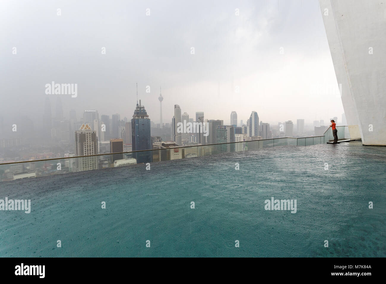 Kuala Lumpur skyline un jour de pluie avec une piscine de luxe à l'avant-plan et la femme profitez de l'avis Banque D'Images