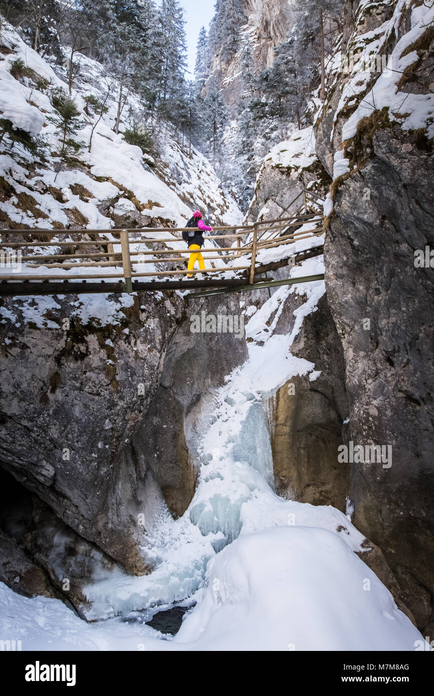 Les jeunes femmes randonner Échelles de bois et des ponts couverts de neige par Baerenschuetzklamm avec gorge glacée congelés cascades Banque D'Images