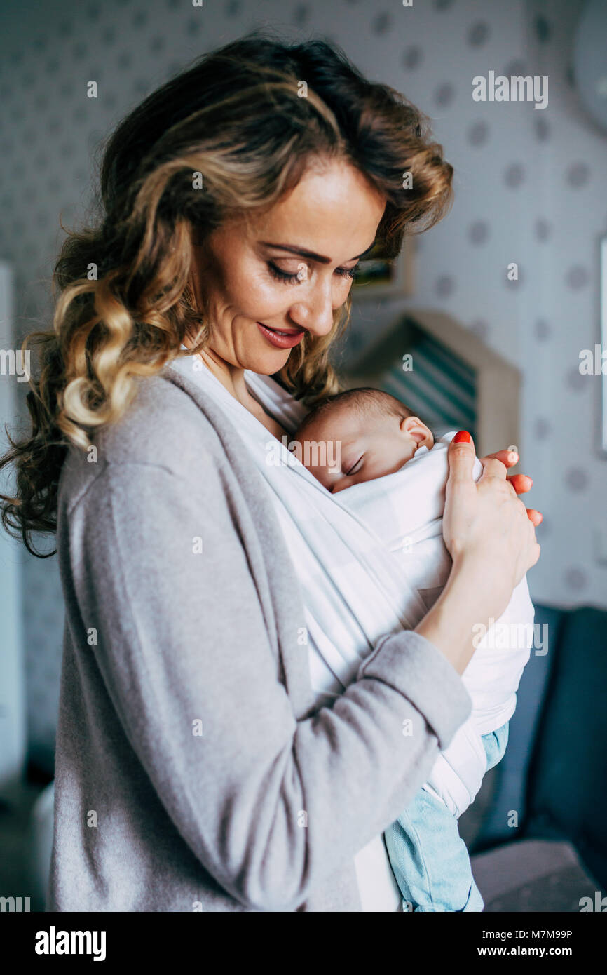 Une maman fière de son fils dans une écharpe et regardant en bas vers lui  alors qu'il est en train de dormir paisiblement Photo Stock - Alamy