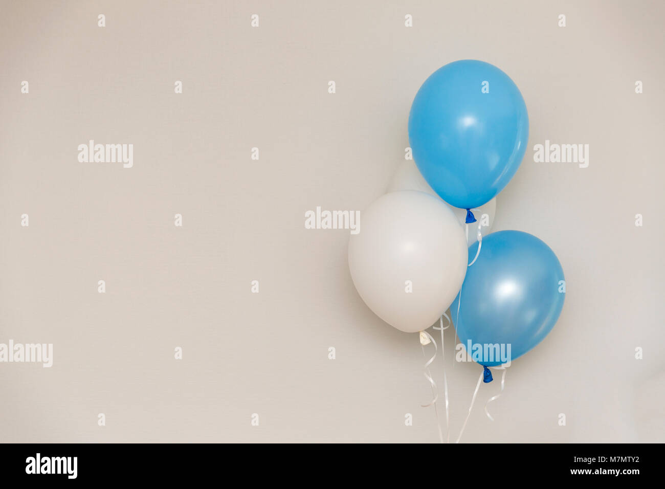 Ballons bleus et blancs sur fond de mur gris clair. L'évidence partie. Banque D'Images