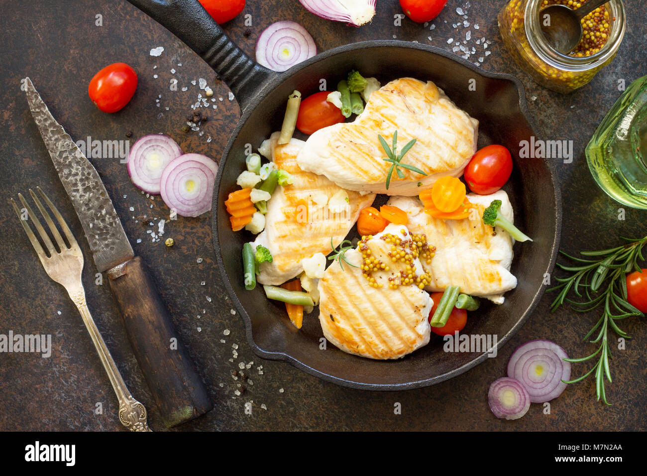 Filet de poulet grillé et légumes divers sur un poêle en fonte. Vue de dessus, l'espace de copie mise à plat arrière-plan. Banque D'Images