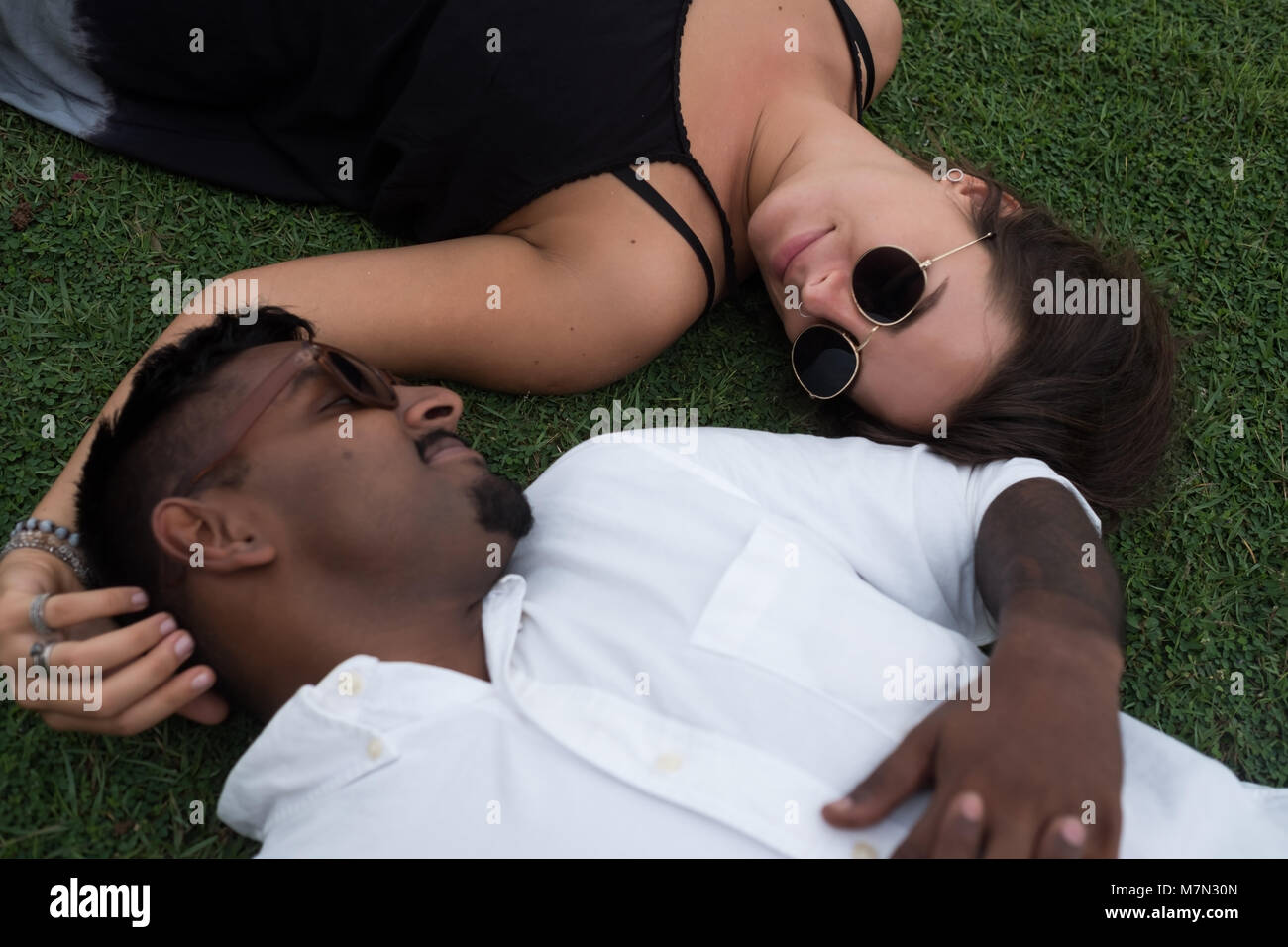 Portrait de mariés couple lying on grass ensemble dans l'amour. Concept de mariage international. Banque D'Images