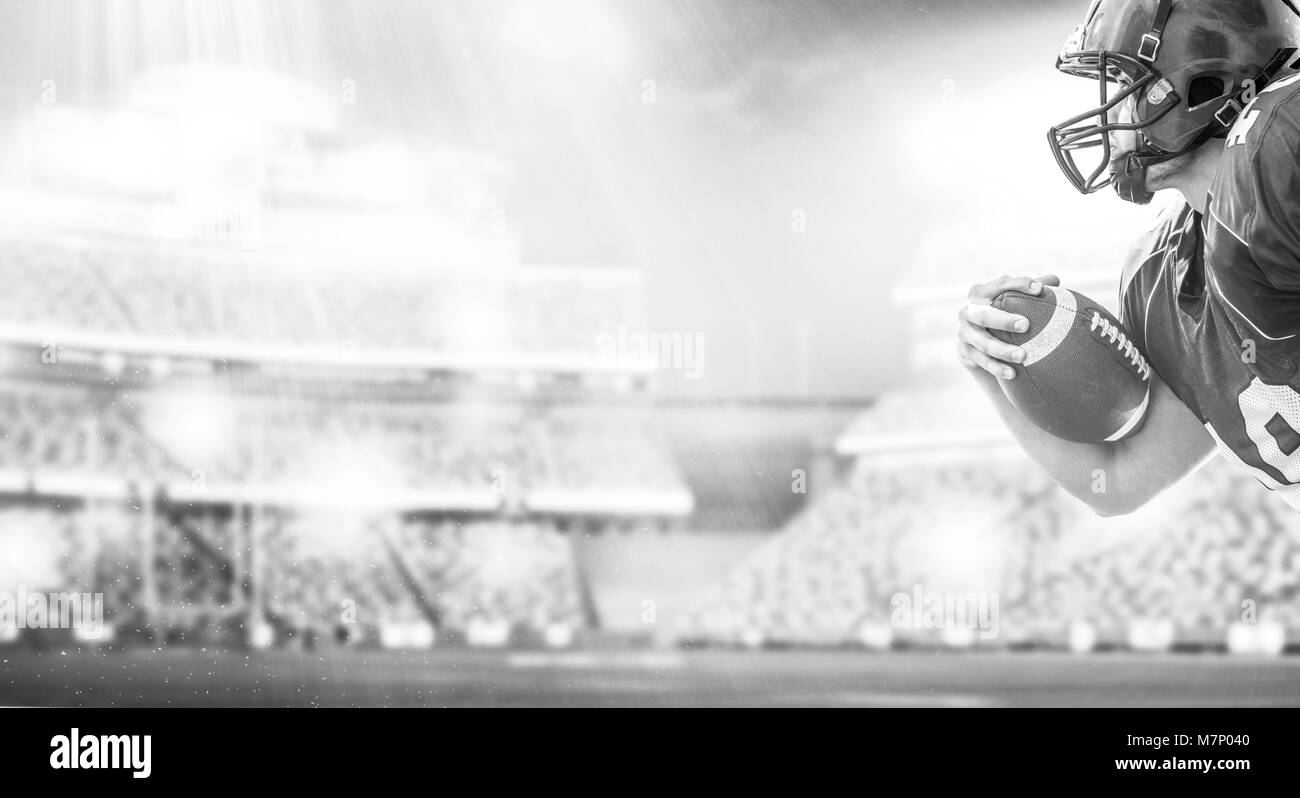 American Football Player exécutant avec la balle isolé sur grand terrain du stade moderne avec des lumières et des fusées éclairantes Banque D'Images