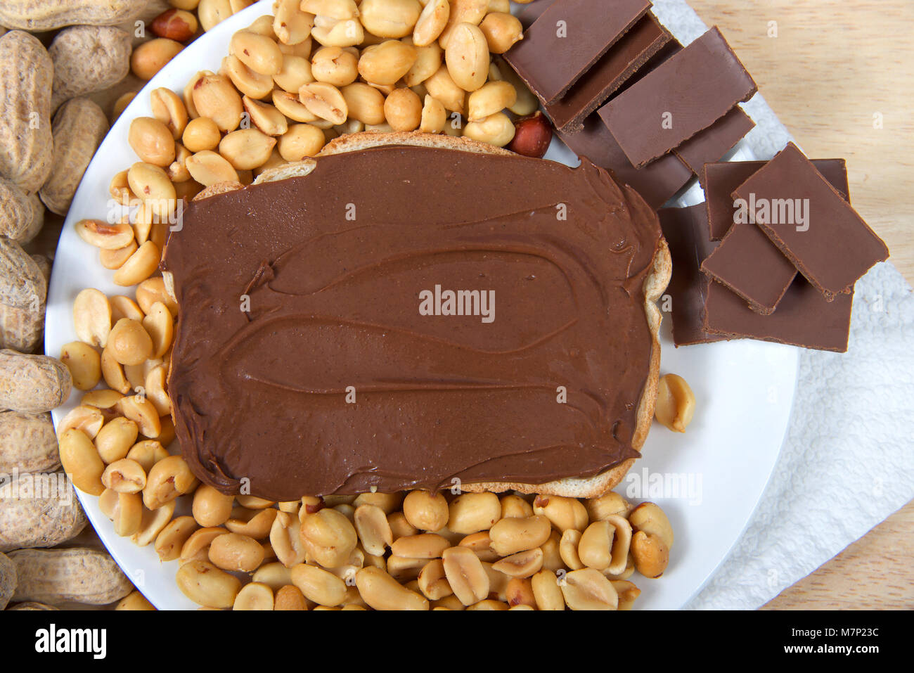 Peanutbutter chocolat tartiner le pain, face ouverte sur la plaque sandwich avec des morceaux de chocolat, arachides décortiquées arachides en coque entier et sur table en bois Banque D'Images