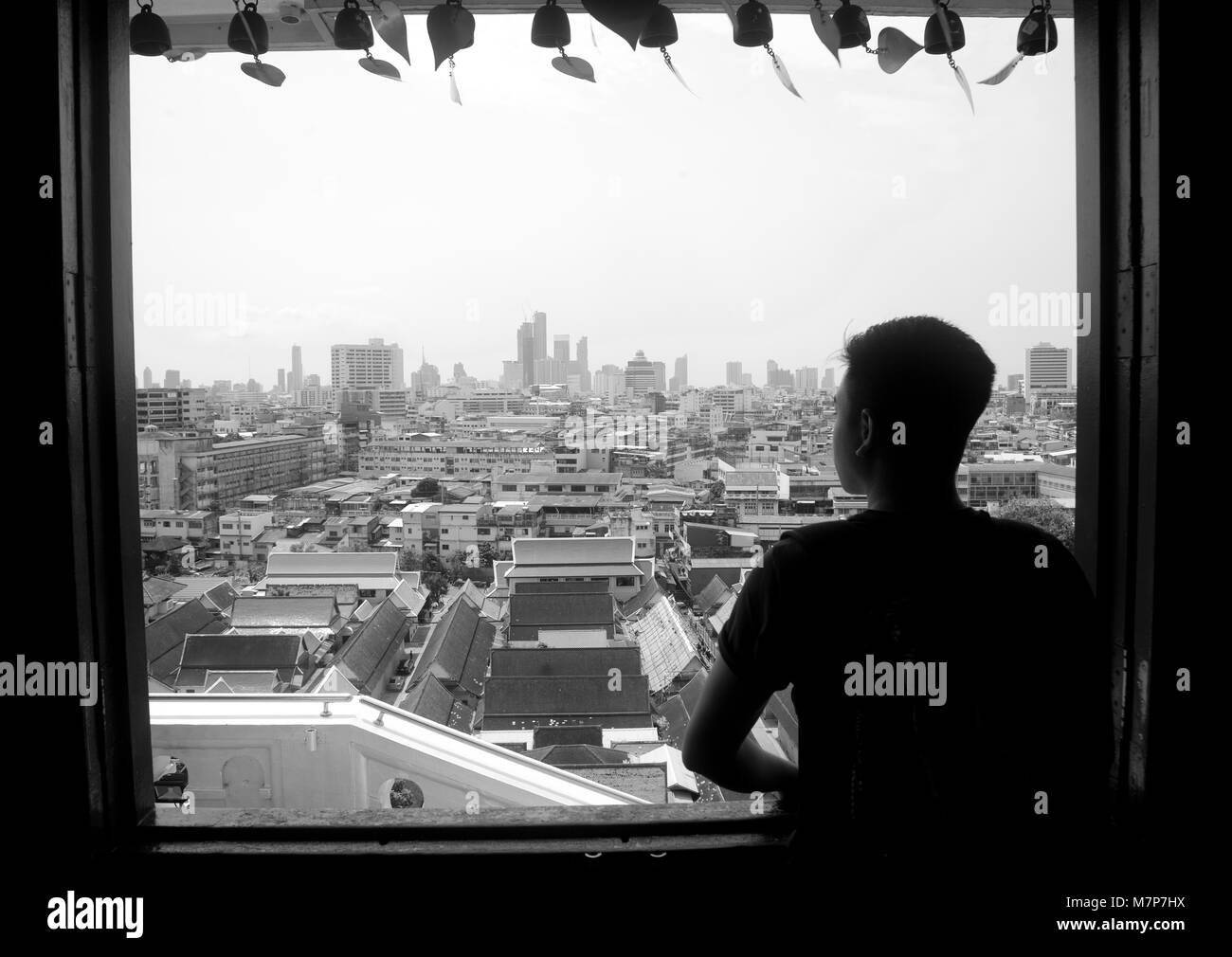 Un jeune homme à la recherche d'une fenêtre sur l'horizon de Bangkok, Thaïlande Banque D'Images