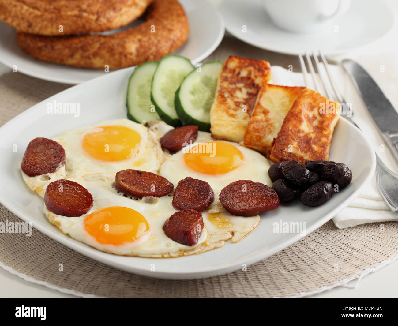 Petit déjeuner turc avec œuf frit, sucuk halloumi, fromage, légumes, simit, et café Banque D'Images