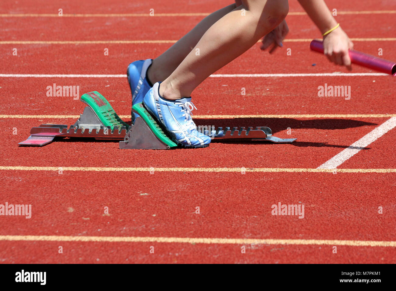 Runner laissant starting-blocks avec baton Banque D'Images