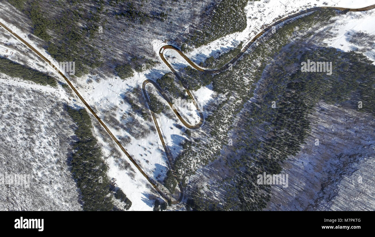 Paysage aérien avec de nombreux arbres et sinueuse route de montagne avec des voitures et de camions dans l'hiver. Banque D'Images