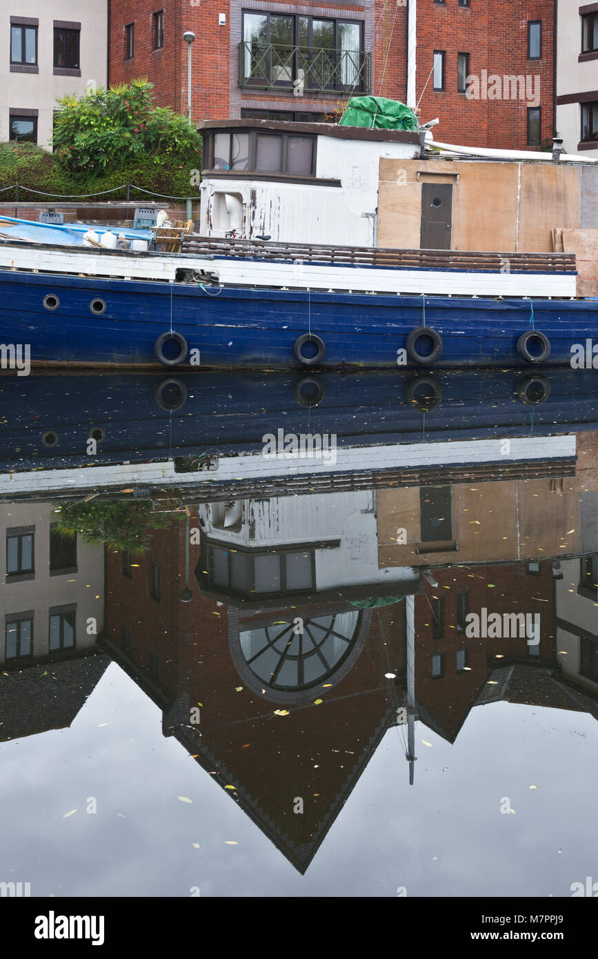 La réflexion d'un vieux bateau en bois amarré le long des rives du canal d'Exeter sur Exe Valley Way juste au sud d'Exeter, Devon, Angleterre Banque D'Images