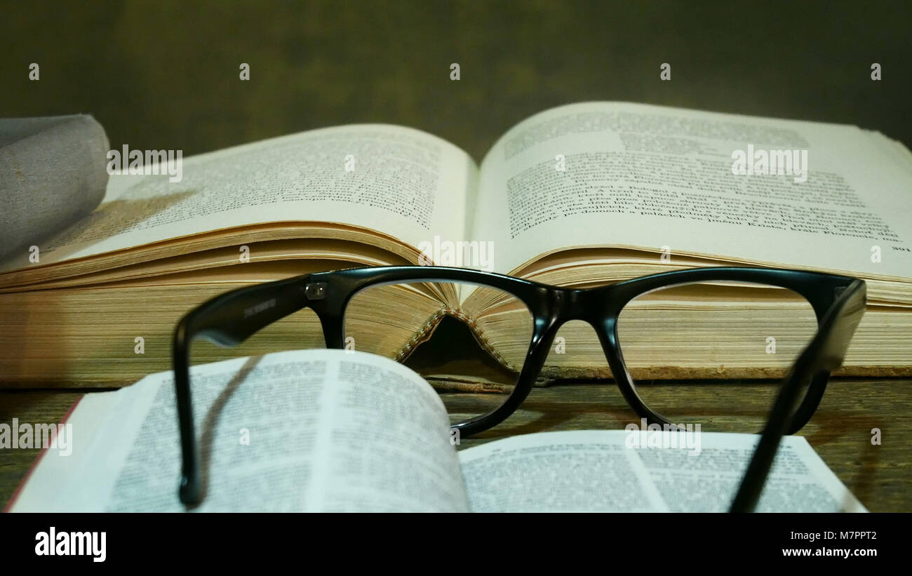 Bible ouverte avec des lunettes sur l'ancienne table. Banque D'Images