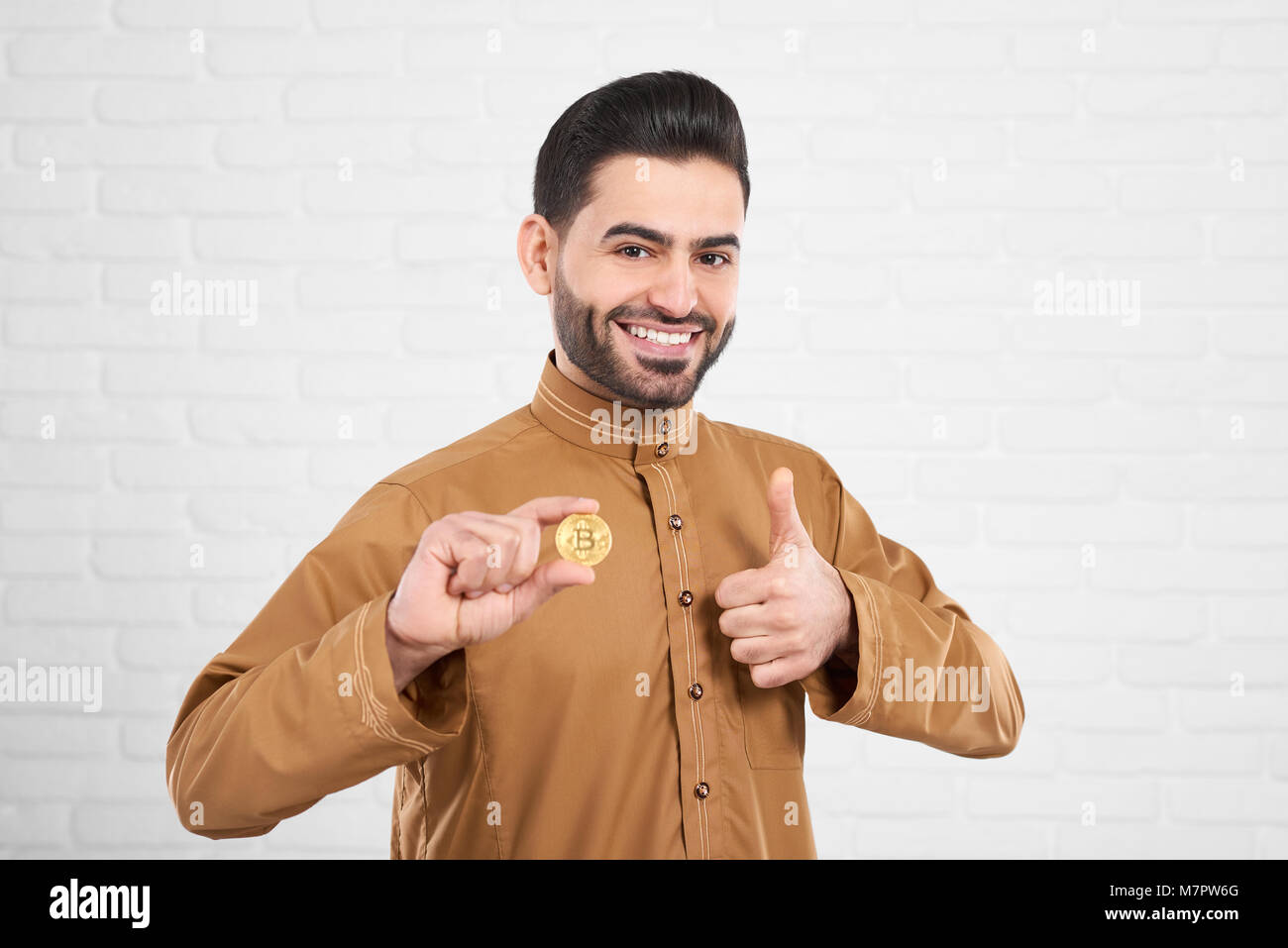 Beau sourire modèle musulmane traditionnelle de vêtements Islamiques posant avec bitcoin or Banque D'Images