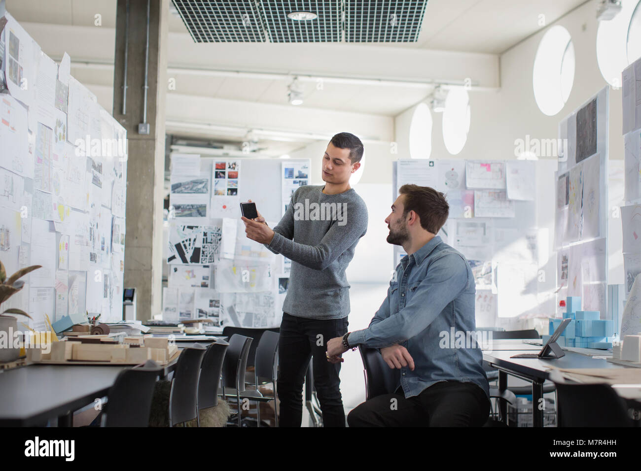 Designers looking at smartphone dans l'espace créatif Banque D'Images