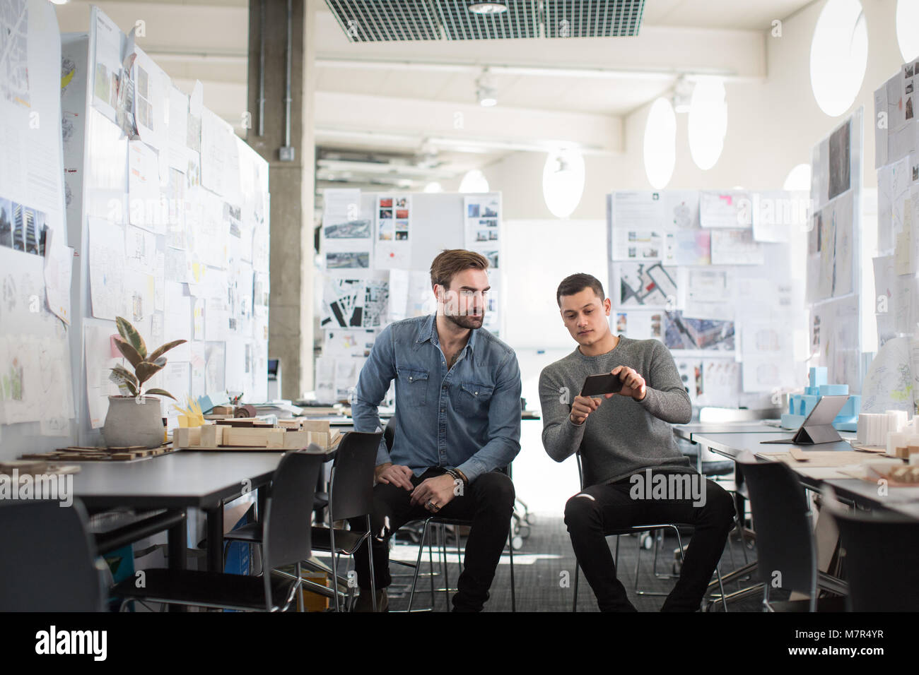 Designers looking at smartphone dans l'espace créatif Banque D'Images
