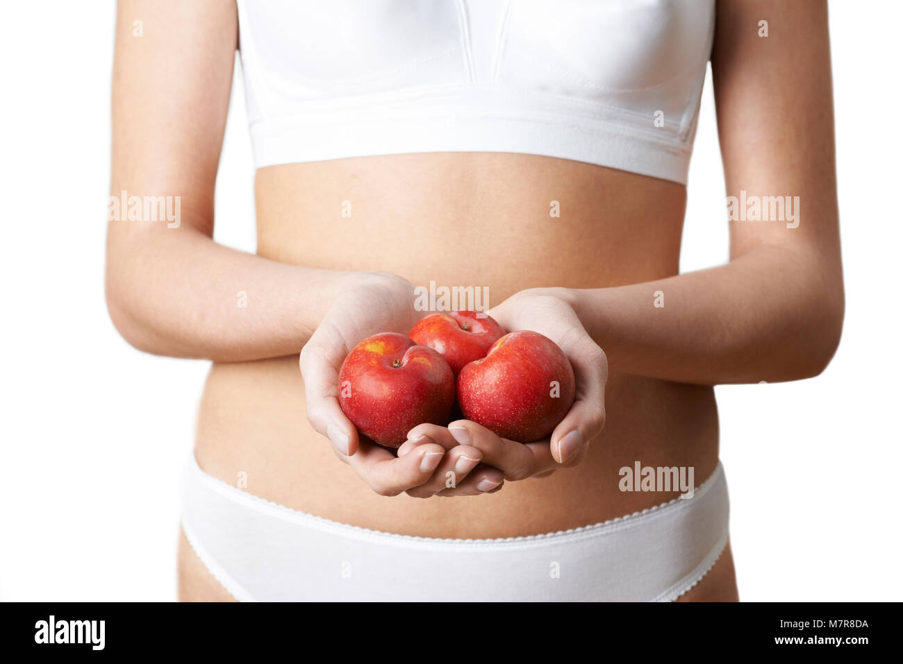 Close Up of Woman in Underwear Holding prunes fraîches Banque D'Images