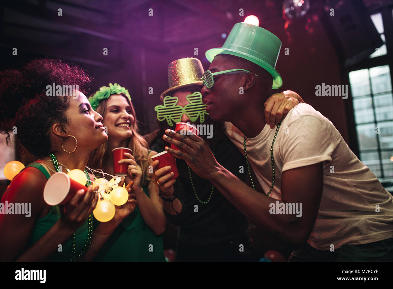Multi-ethnic hommes et femmes s'amuser au bar. Groupe d'amis pour célébrer le Jour de la Saint Patrick en discothèque. Banque D'Images