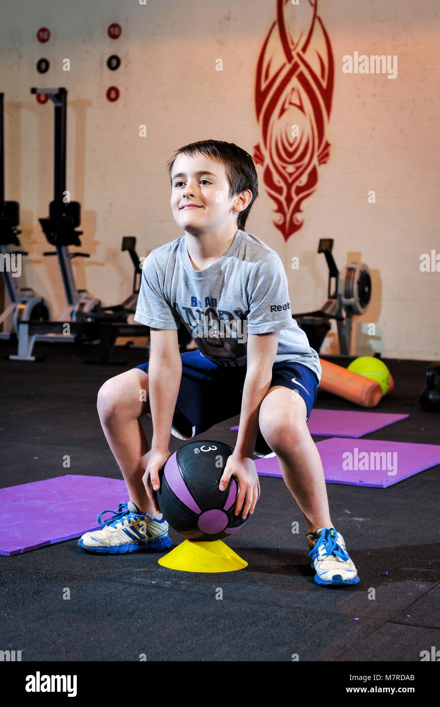 Un jeune garçon à la levée de poids sous la supervision d'un instructeur de Fitness. Banque D'Images