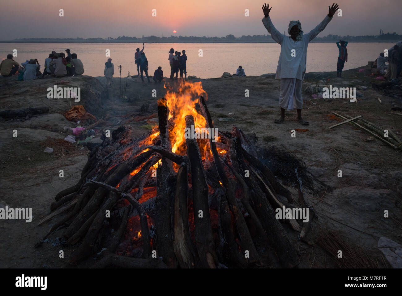 Le bûcher au coucher du soleil avec son fils est élevé mains en arrière-plan durant Kartika Purnima (Deva-Diwali Konhara), Ghat, Hajipur, Inde. Banque D'Images