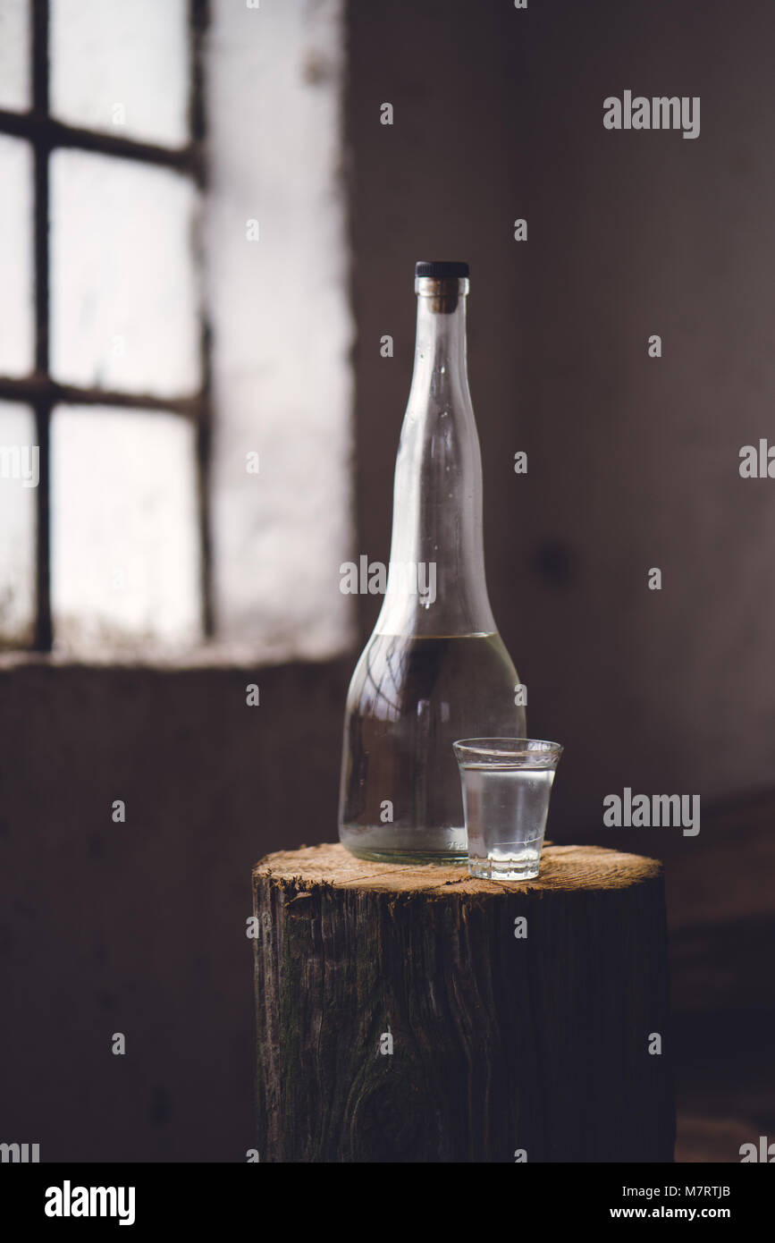 Boire de l'alcool fort en bouteille avec coup du verre dans l'atmosphère rustique traditionnel aux couleurs rétro Banque D'Images