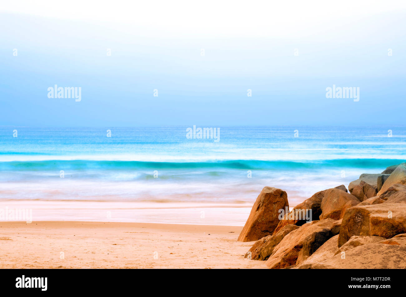 Journée calme relaxant à la plage avec des vagues roulant sur la plage de sable doré. Banque D'Images