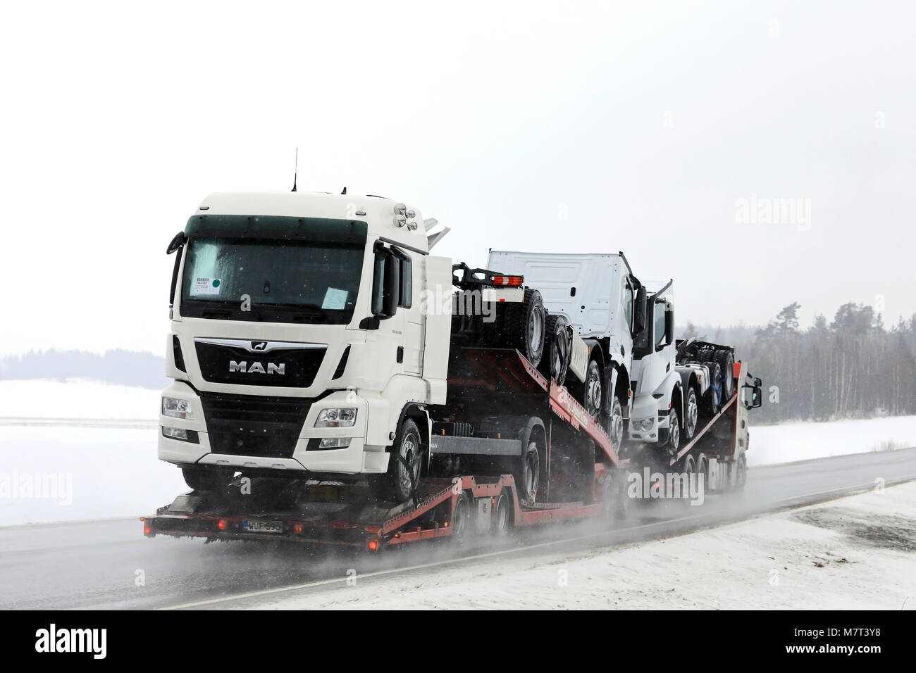 SALO, FINLANDE - le 9 mars 2018 : véhicule transporteur transporte homme nouveau et Mercedes-Benz camions lourds sur route mouillée dans la neige dans le sud de la Finlande. Banque D'Images