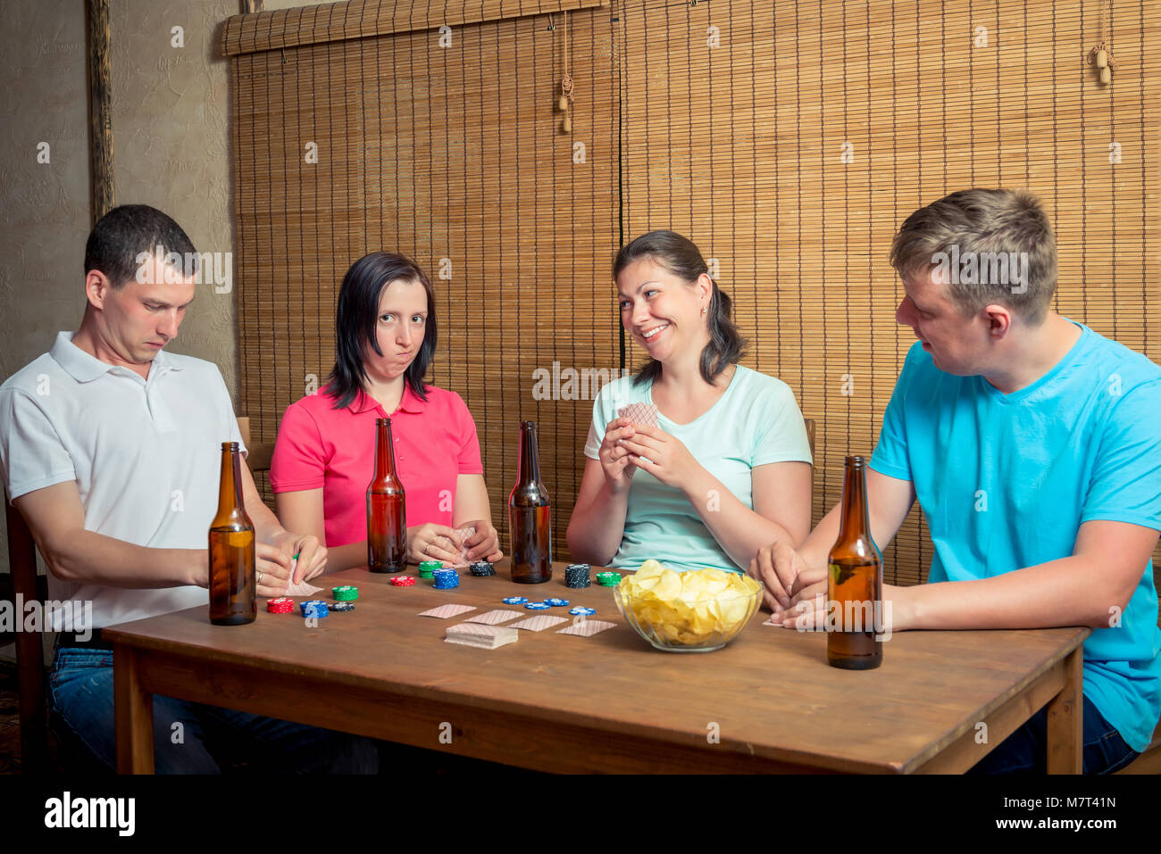 Quatre amis jouer aux cartes assis à une table à l'intérieur, la consommation de bière Banque D'Images