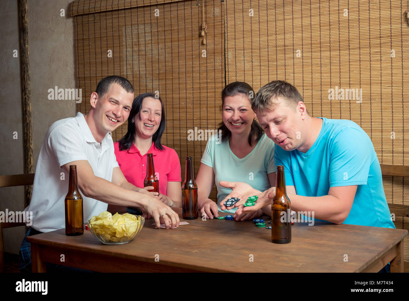 Jeune et heureux quatre amis en jouant au poker à la table et boire de la bière Banque D'Images
