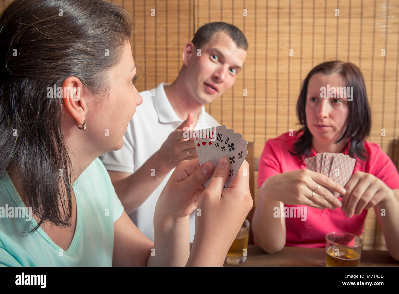Homme et deux femmes jouant au poker, une femme montrant leurs cartes Banque D'Images