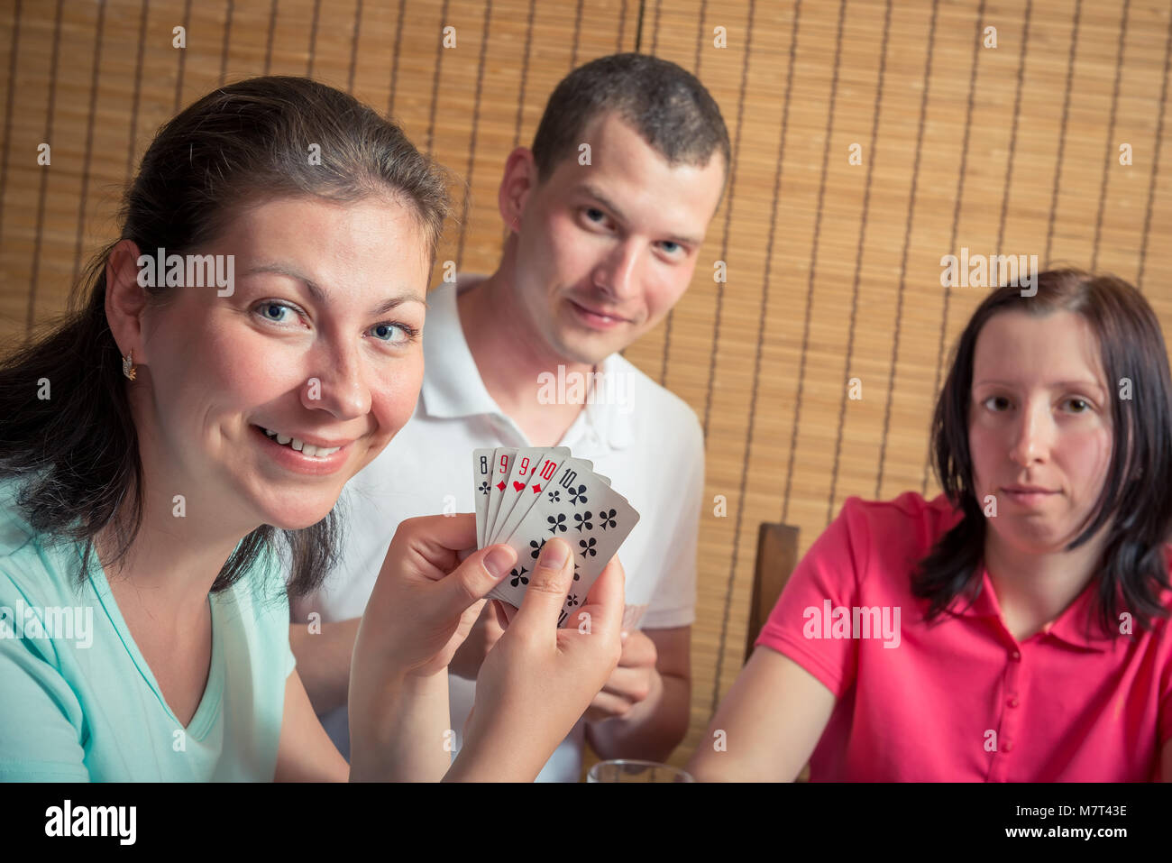 Homme heureux et deux femmes jouant au poker, une femme montrant leurs cartes Banque D'Images
