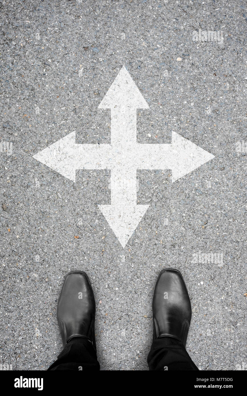 Chaussures noires debout à la croisée de décider où aller. Gauche, droite, en avant ou en arrière. Est, ouest, nord ou sud. Banque D'Images
