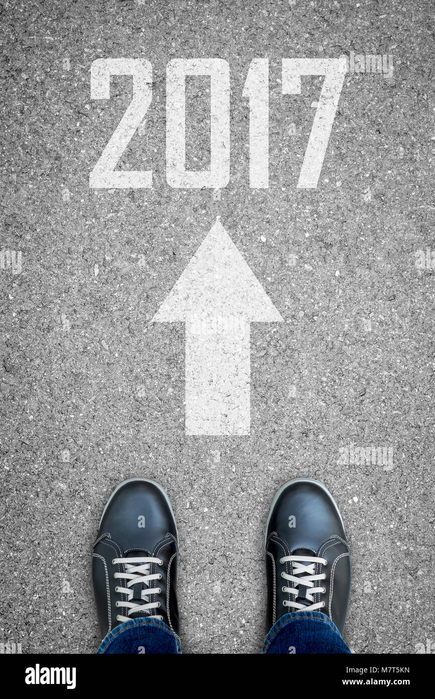 Les chaussures noir debout sur la route de béton bitumineux et blanc direction raconter pour aller directement au nouvel an 2017 Banque D'Images