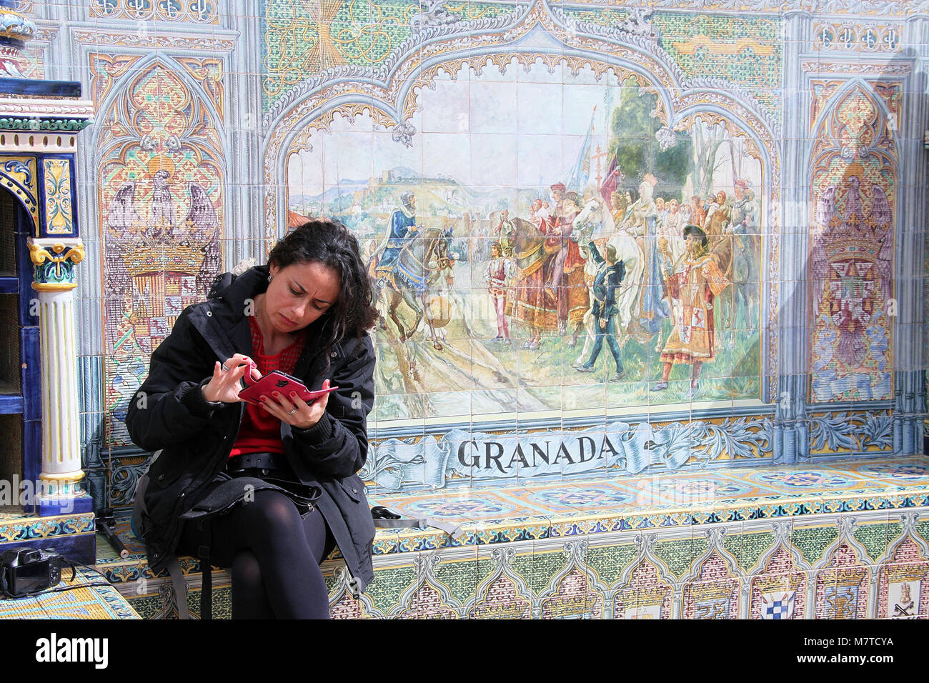 Contrôle de femme son téléphone assis dans une alcôve provincial à la Plaza de España à Séville Banque D'Images