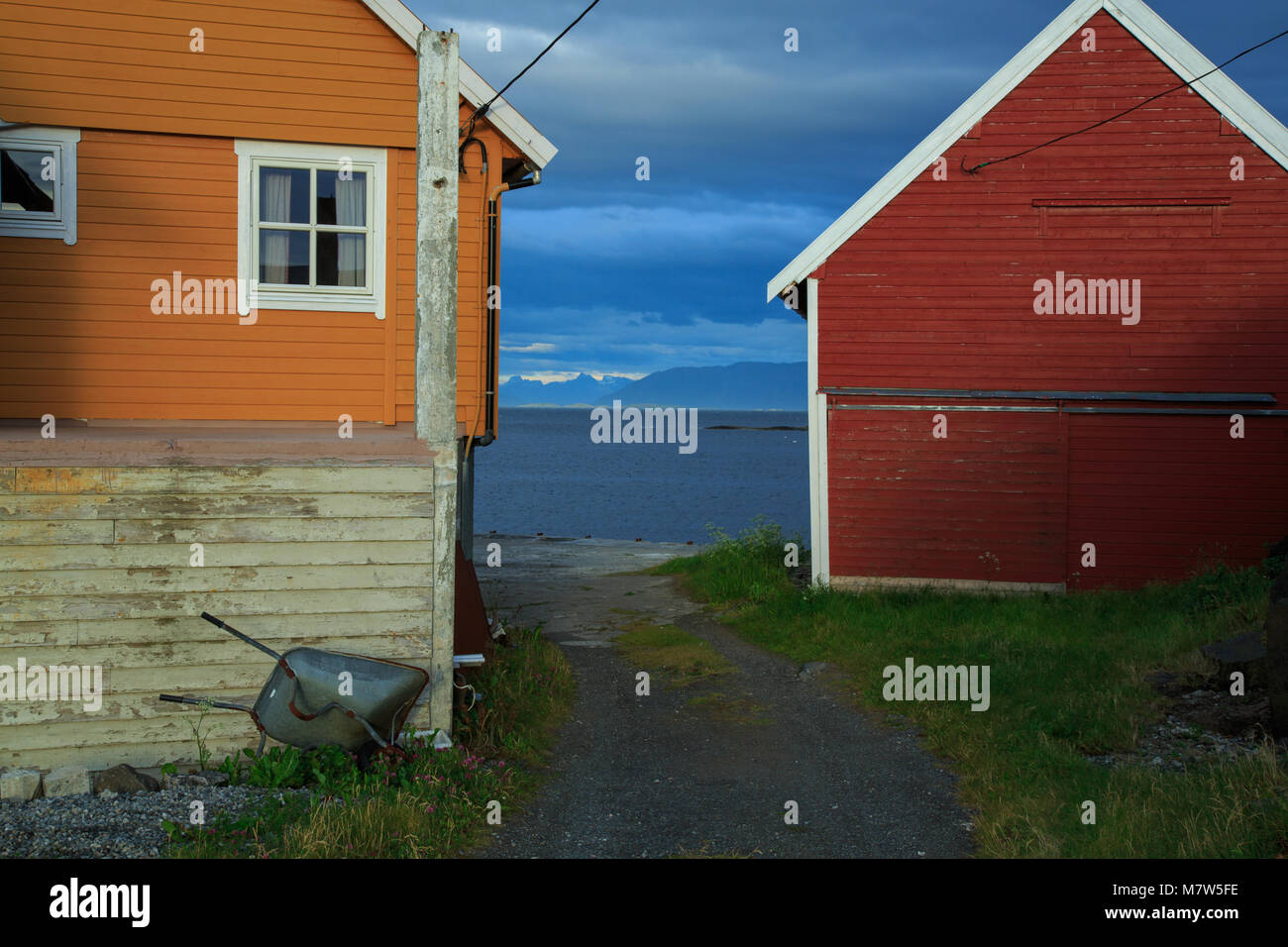 Maison en bois rouge et orange par la côte de l'île de la Norvège avec l'AIIO étrange nuage sombre Banque D'Images
