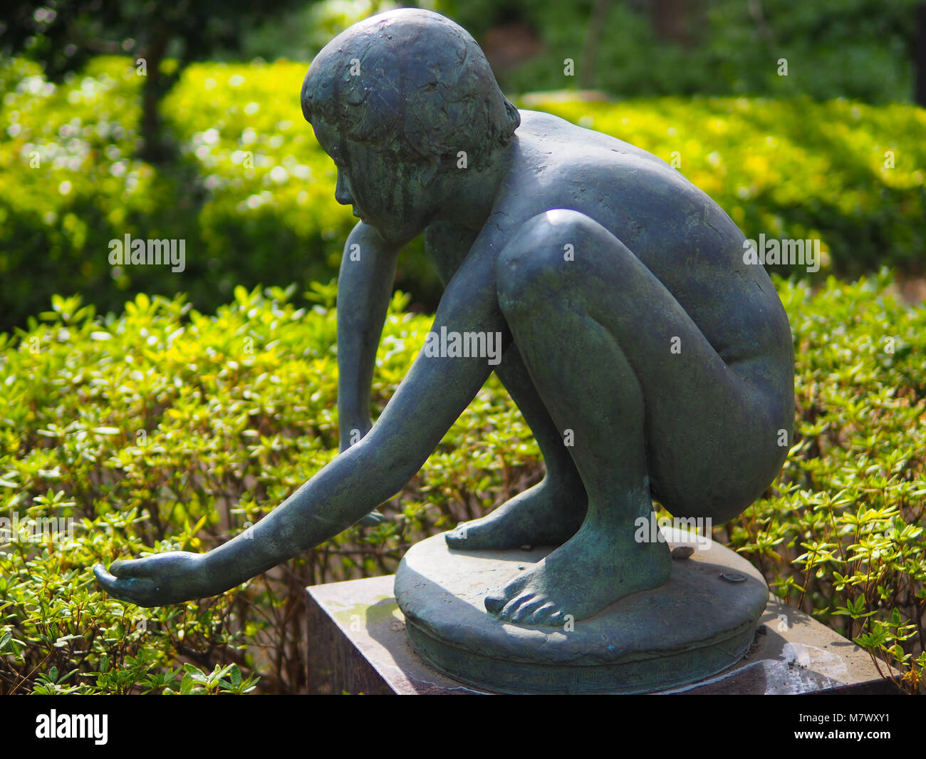 Ancienne statue en bronze de jeune enfant accroupi, Tokyo Japon. Avec bras tendus et bombée main, une magnifique statue en bronze d'un enfant accroupi. Banque D'Images