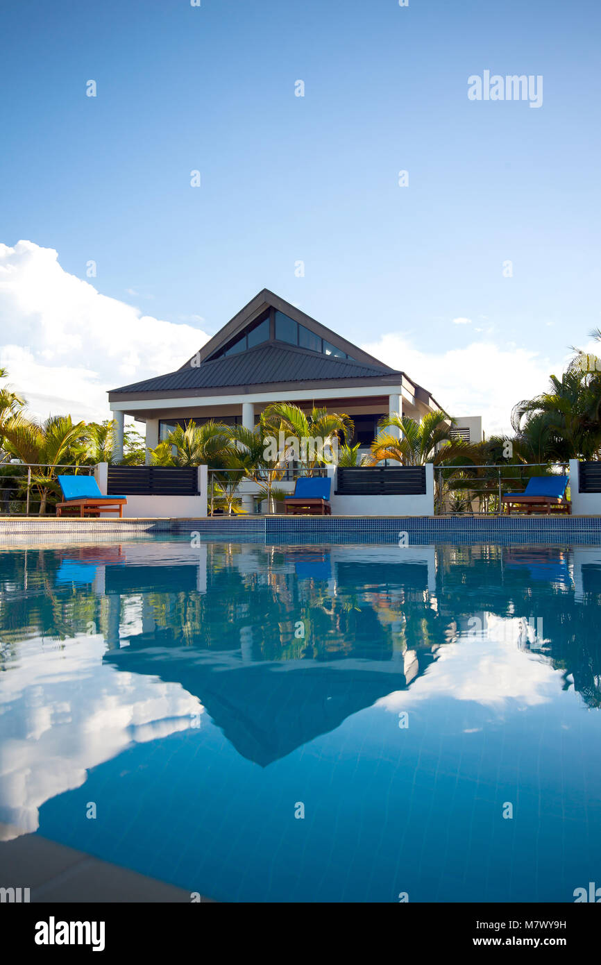 Avis de villa de luxe avec piscine entourée de palmiers et de sièges aux Fidji pendant belle journée ensoleillée et chaude. Banque D'Images