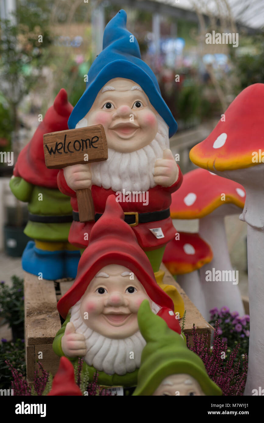 Jardin anglais gnome avec un panneau de bienvenue avec chapeau bleu veste rouge et barbe blanche et toadstool Banque D'Images