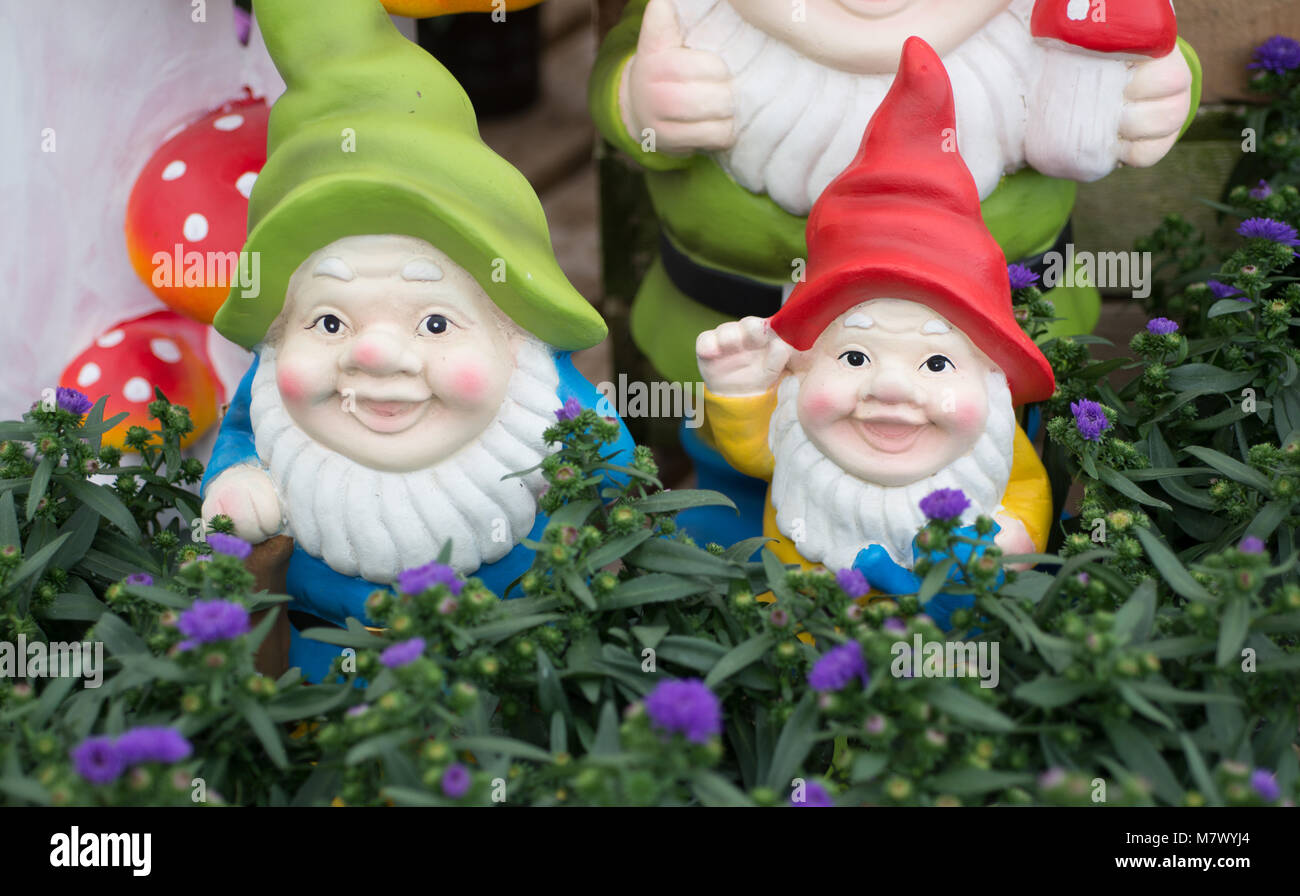 Jardin anglais gnome avec un panneau de bienvenue avec chapeau bleu veste rouge et barbe blanche et toadstool Banque D'Images