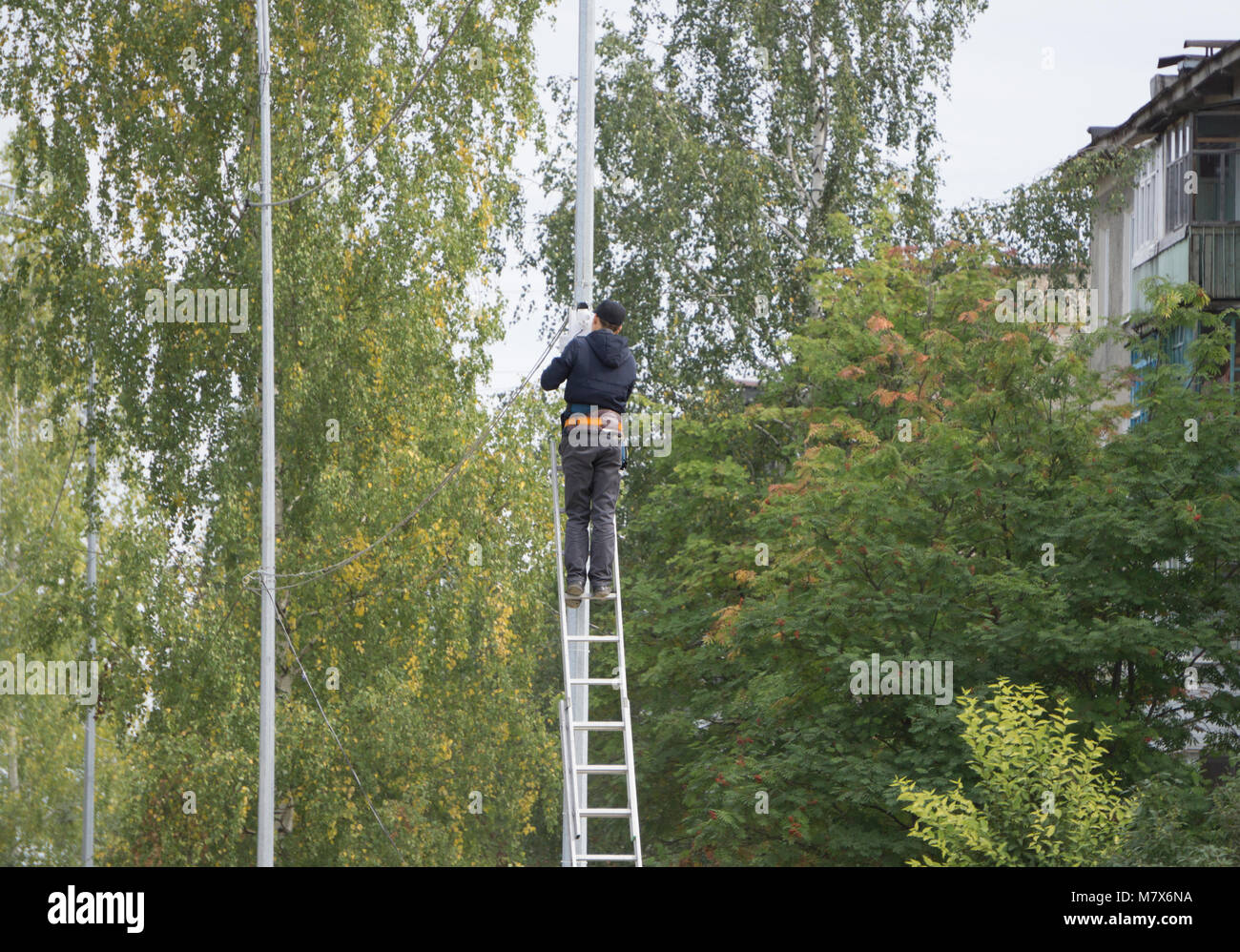 Le technicien est l'escalade sur le poteau électrique pour réparer des problèmes électrique dans le fond de ciel bleu nuageux, notion de risque de danger wo Banque D'Images