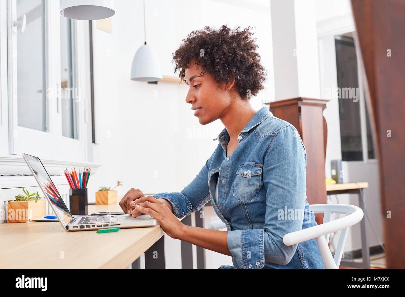 Jeune étudiante multiculturelle à l'e-learning sur ordinateur portable. Dans l'étude de l'ordinateur Banque D'Images