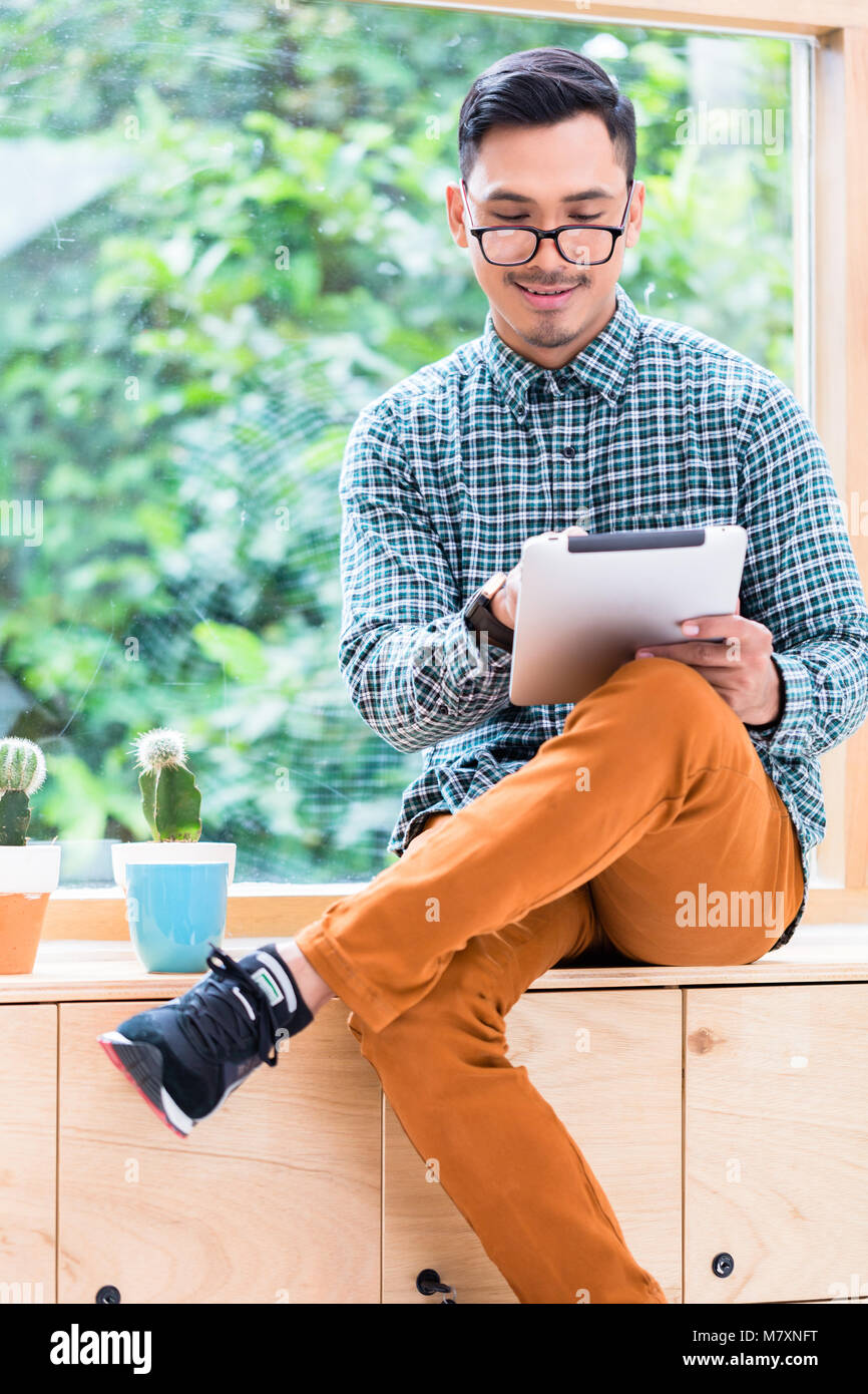 Young Asian man la navigation internet sur un tablet PC au bureau Banque D'Images