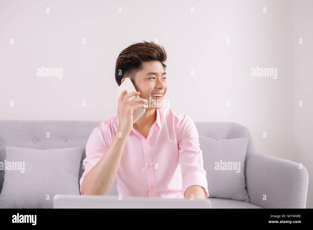 Beau jeune homme asiatique avec un ordinateur portable sur le téléphone Banque D'Images