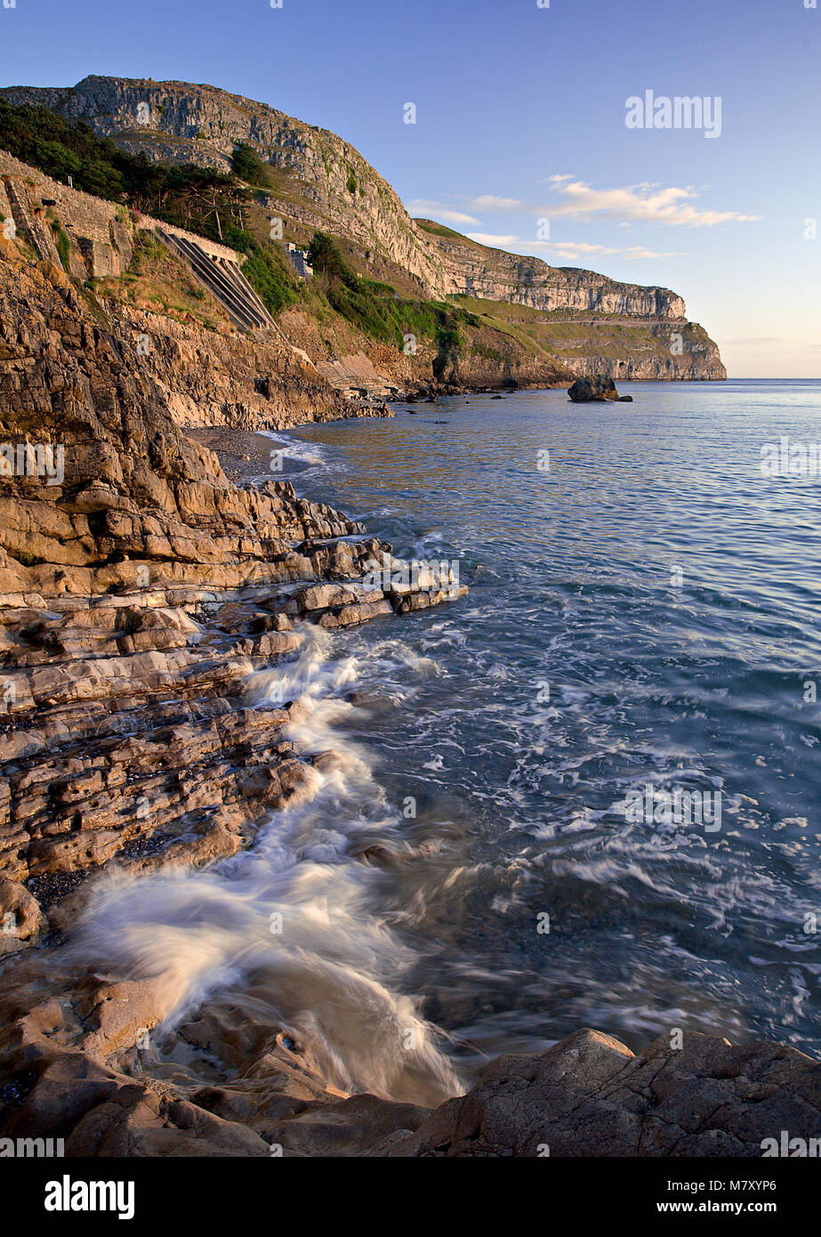 Vagues se brisant au pied du Great Orme, Llandudno, côte Nord du Pays de Galles au lever du soleil Banque D'Images