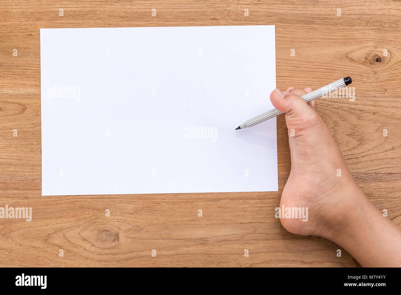 Vide de papier blanc et le pied droit des personnes handicapées avec un crayon sur un bureau en bois. Utilisez pour mobilité concept. L'accent sur pied vue supérieure Banque D'Images