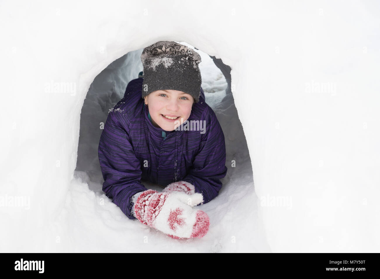 Canadian girl smiling et reposant sur les coudes à la sortie d'un tunnel sous la neige Banque D'Images