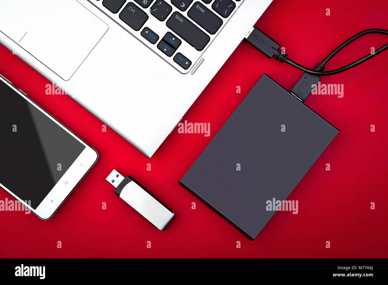 Disque dur externe connecté à l'ordinateur portable, un lecteur flash USB  et smartphone sur un fond rouge, mise à plat. Le concept de la technologie  mobile Photo Stock - Alamy