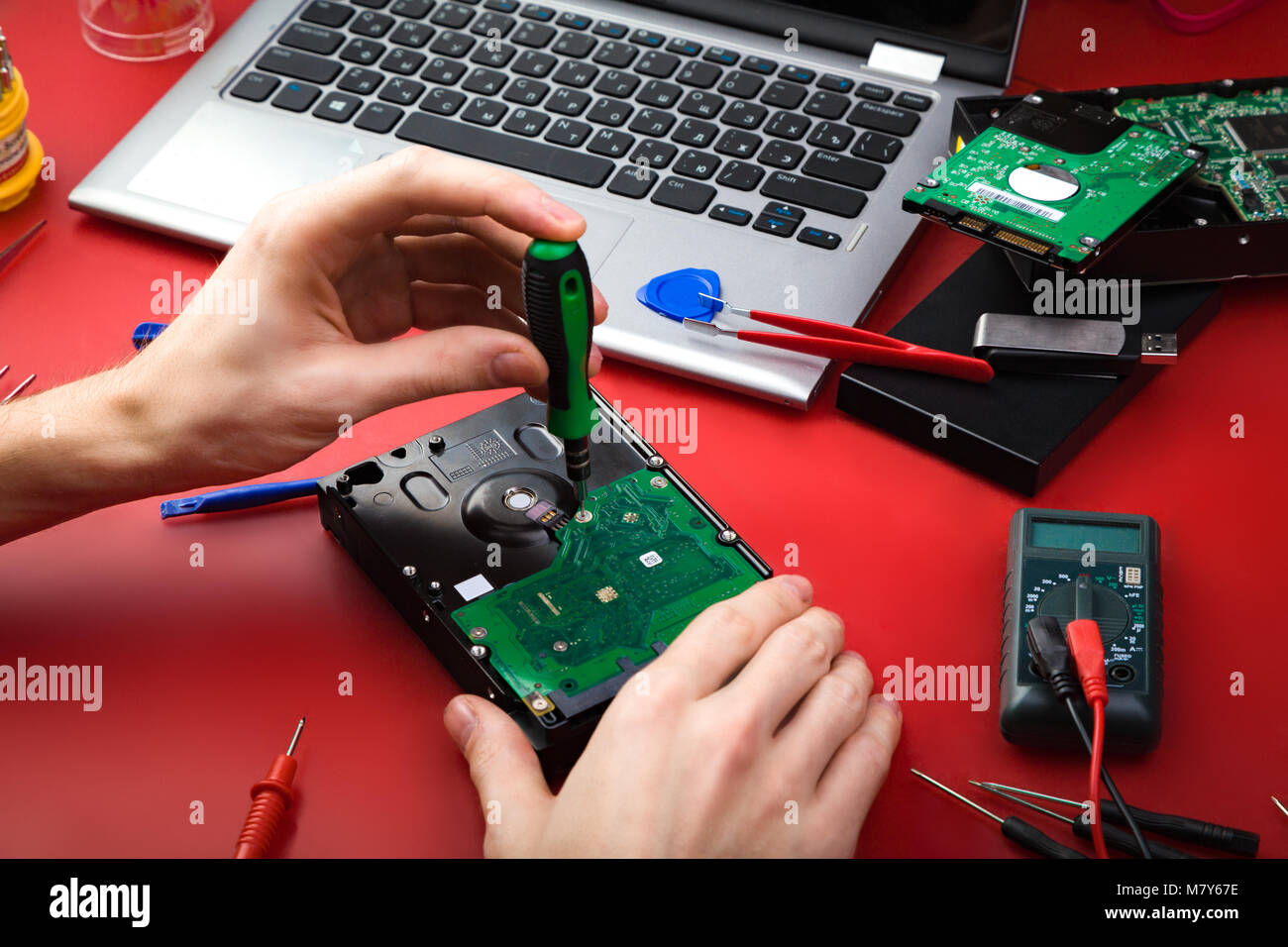 Réparer un disque dur avec un ordinateur portable et des outils spéciaux  sur une table rouge. Lieu de travail de réparateur Photo Stock - Alamy