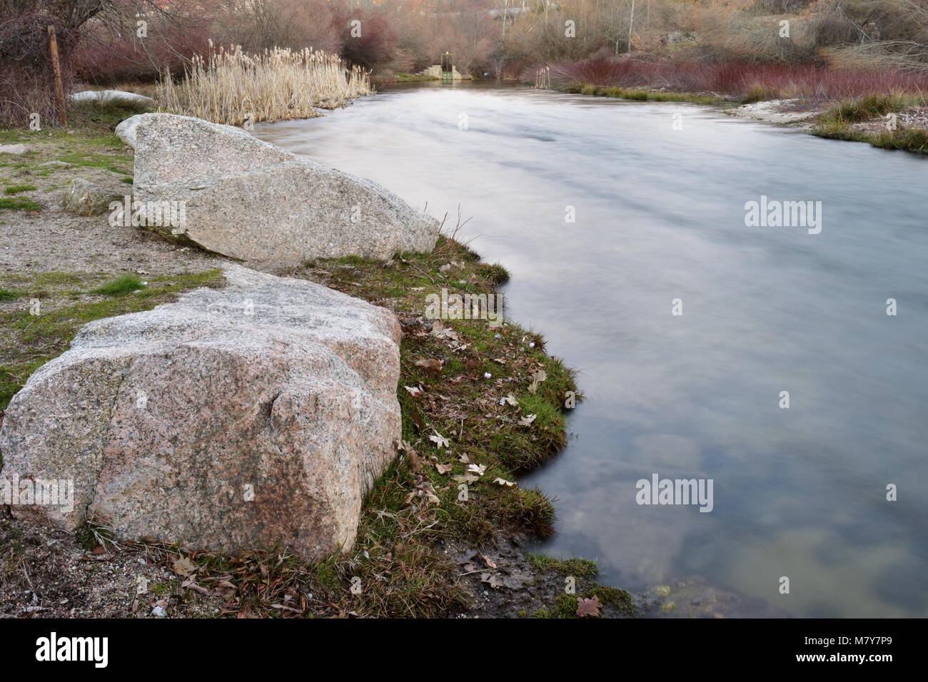 Petite rivière fluide au crépuscule avec de gros rochers sur la rive Banque D'Images