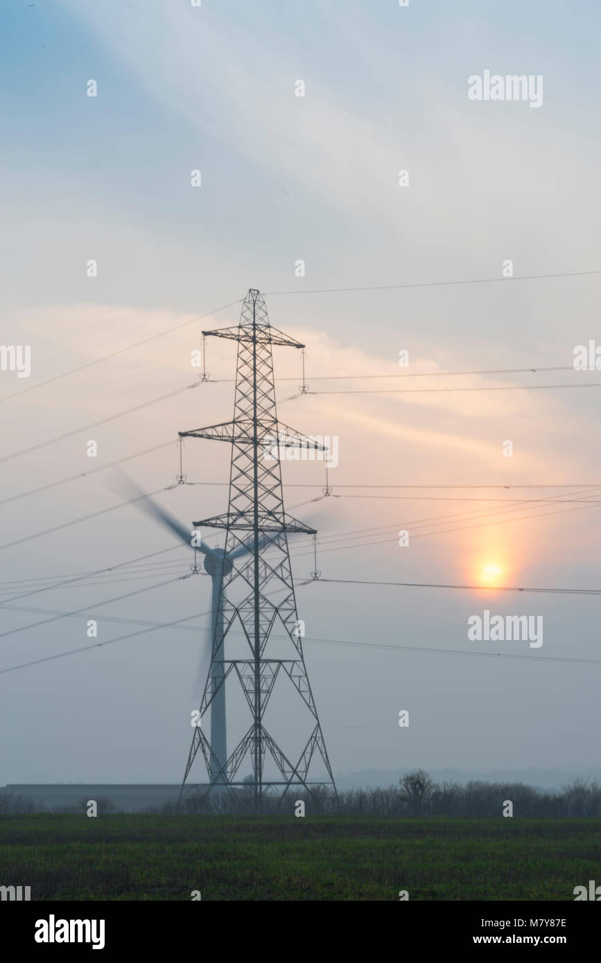 L'électricité éolienne et pylône au coucher du soleil Banque D'Images