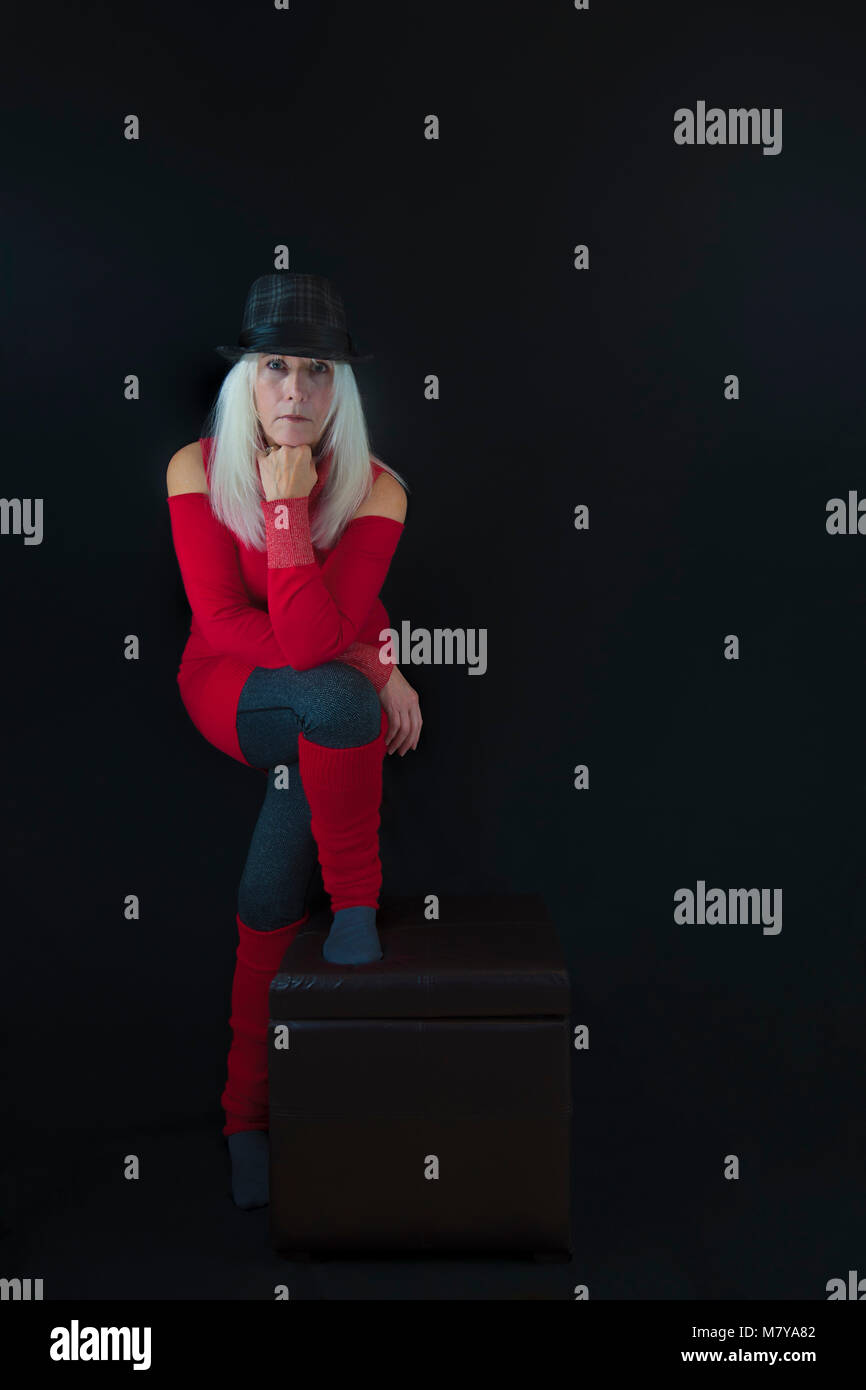 Copyspace disponible sur fond noir d'une femme mature habillé en pull rouge et gris, poignées en chaussettes et leggins et gris et chapeau noir, et lo Banque D'Images