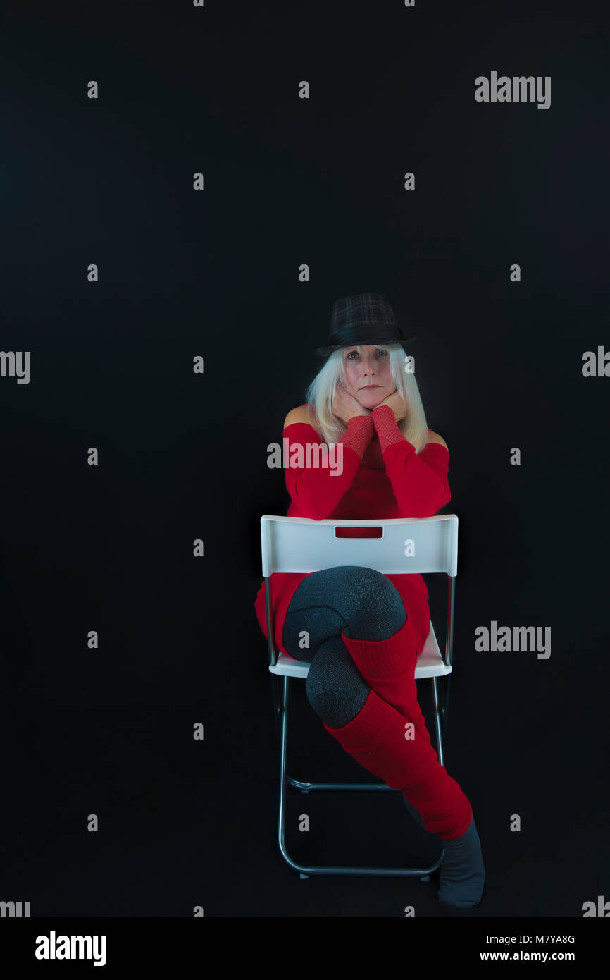 Copyspace disponible sur fond noir en mode portrait Portrait d'une femme mature habillé en pull rouge et gris, poignées et leggins chaussettes et gra Banque D'Images